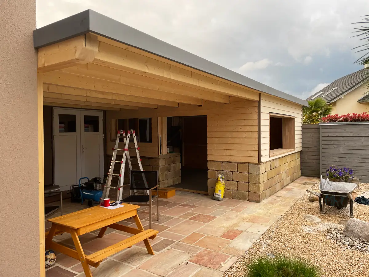Abri de jardin en bois avec toiture plate, construit dans une cour résidentielle.